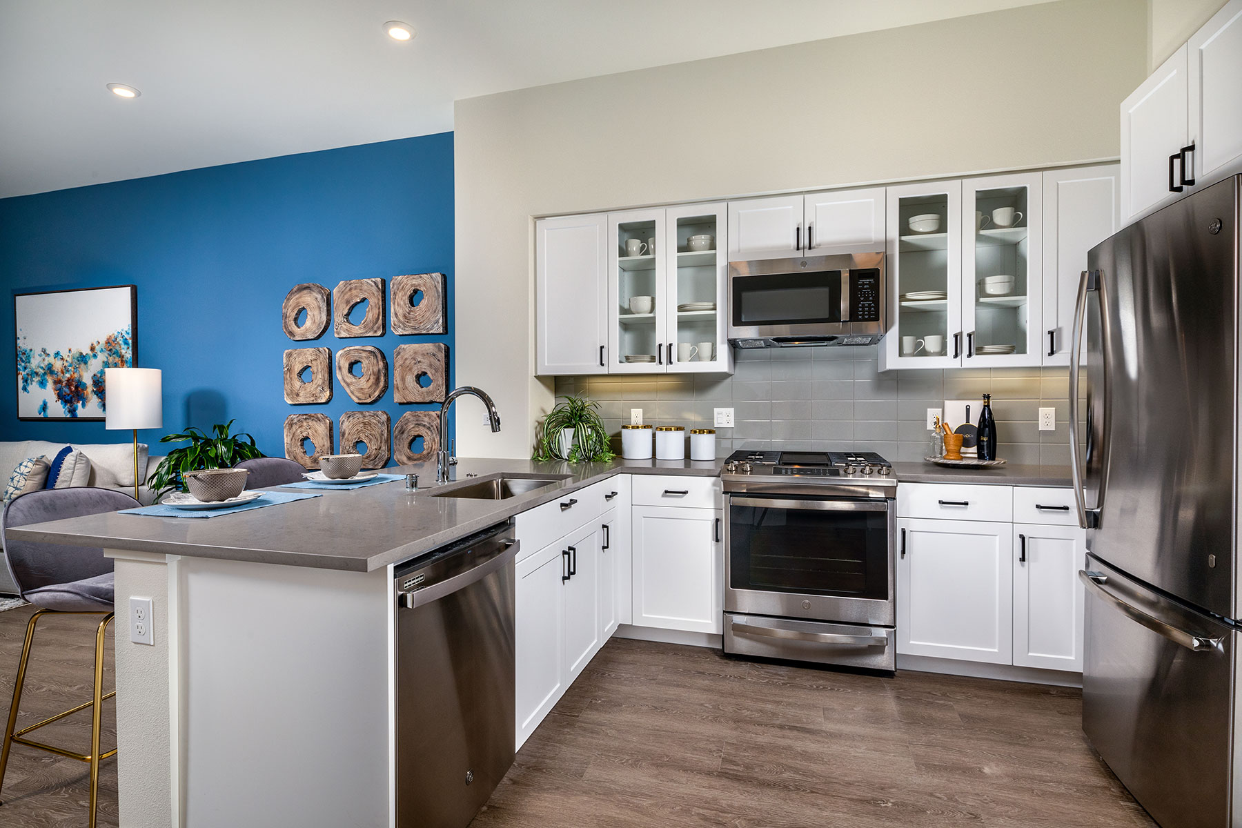 San Mateo Apartments for Rent - Azara - Kitchen with White Cabinets, Glass Door Cupboards, Grey Quartz Countertops, and Stainless Steel Appliances.
